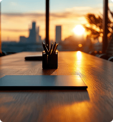 Workspace at sunset with a pen holder on a wooden desk facing the city skyline